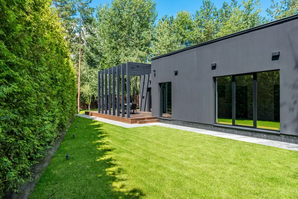Maison récente, pelouse neuve et haie haute en limite de propriété
