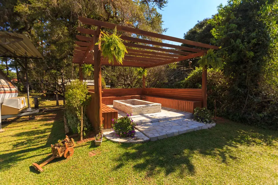 Terrasse en bois sous une pergola, bancs intégrés, au milieu d'une pelouse