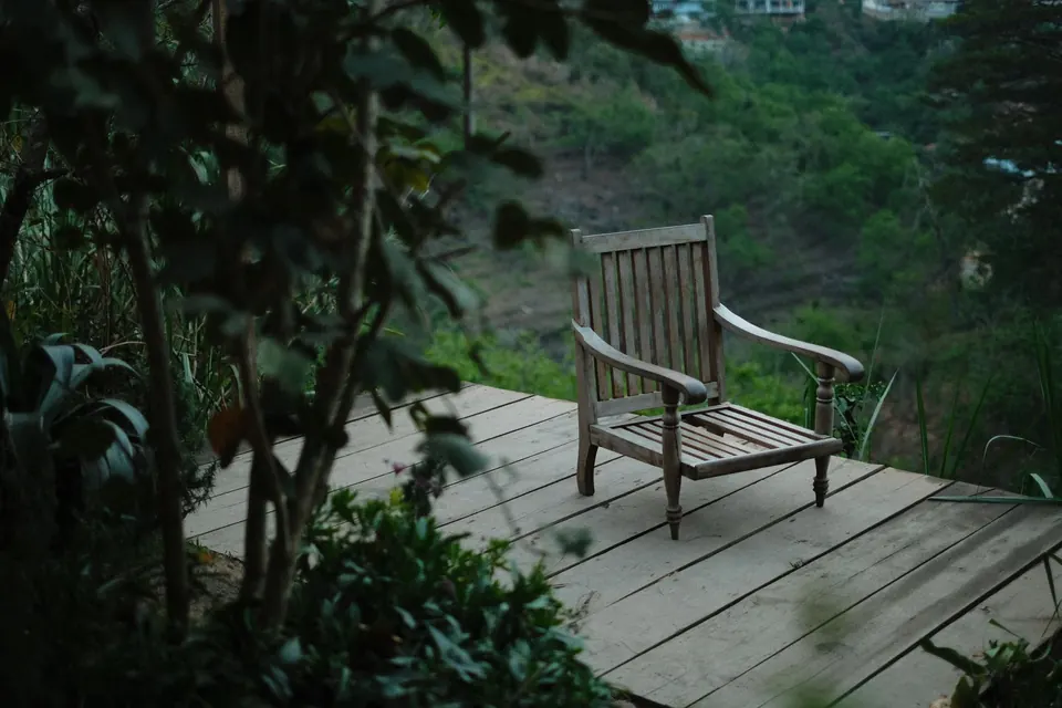 Petite terrasse en lames de bois et fauteuil, en lisière de sous-bois
